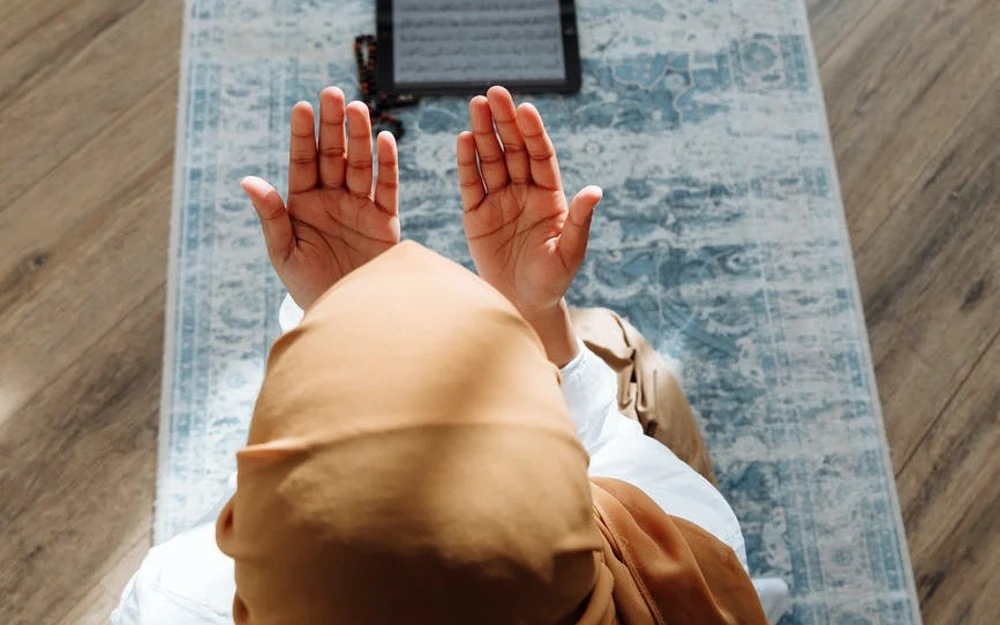 high angle shot of a person kneeling on a blue prayer rug for a natural re-fill