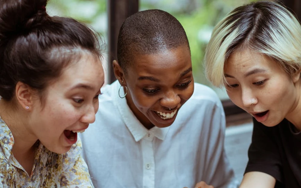 delighted and surprised female friends with laptop and smartphone